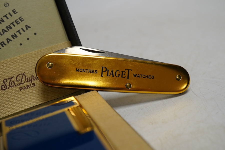 A Dupont gilt metal and blue enamel cigarette lighter with Japanese characters to the side, boxed with papers and a Piaget Montres Watches folding knife, cased. Condition - good